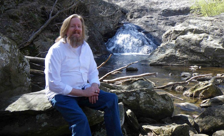 Daniel Green sitting on a big rock by the waterfall talking about His journey to have Heaven follow him