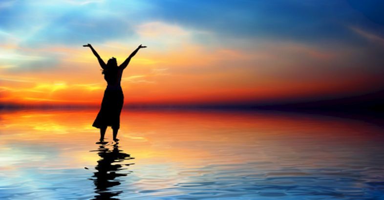 Silhouette of a women walking on water raising her hands to the heavens